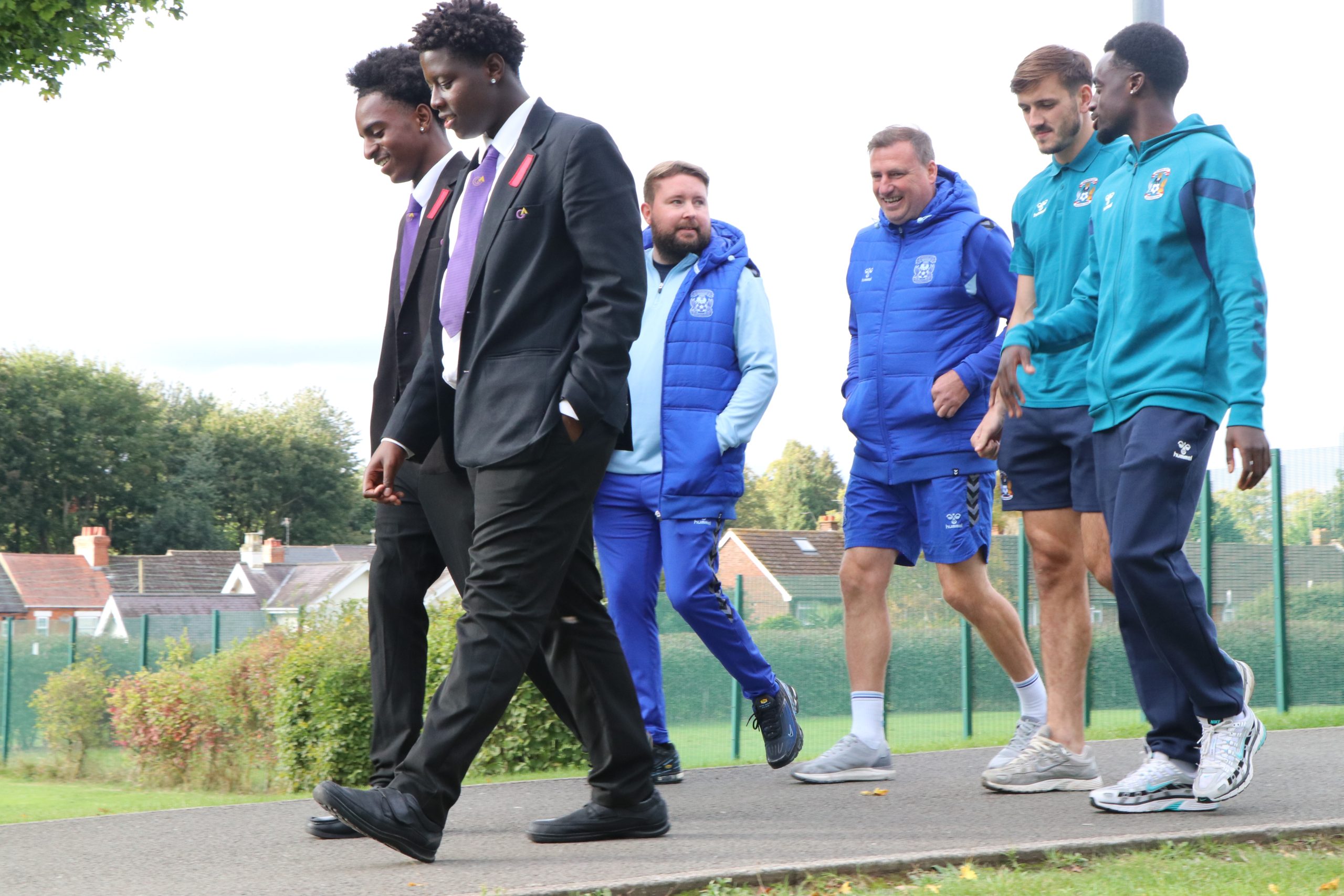 An image of two participants at Active Sky Blues. One person is wearing a black and white striped jumper with black leggings, they are wearing glasses and pink boxing pads on their hands. The other participant has their back to the camera wearing a short sleeved pink top, pink boxing gloves and a pink hijab.